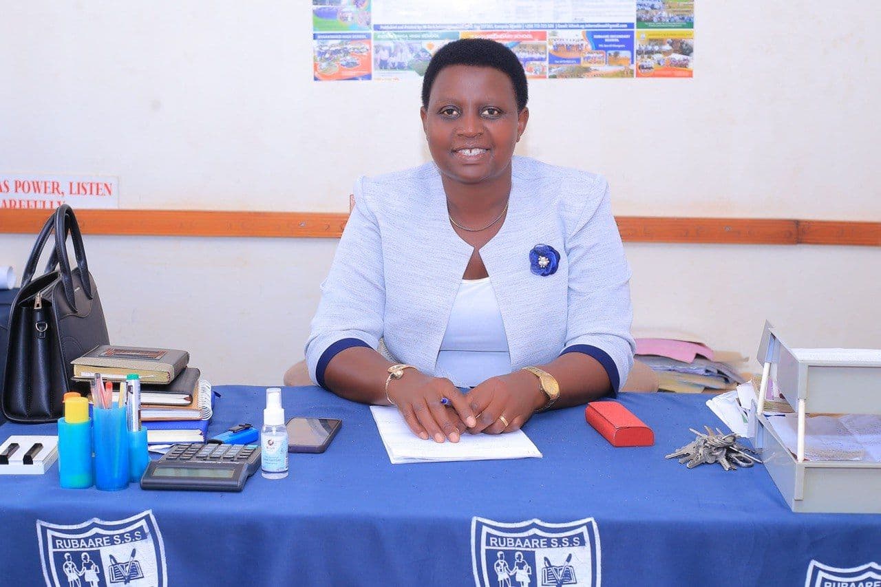 Headteacher Ms. Mpeirwe Monic Atukunda seated at her desk.